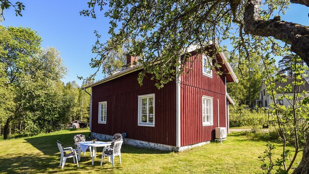 A red wooden house with a white porch and a small table with chairs. - Nice Home in Munkedal With 2 Bedrooms and Wifi (Munkedal)
