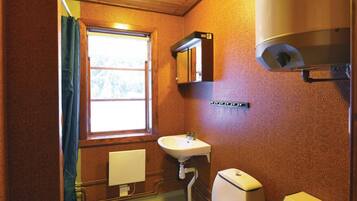 Un baño con ventana, lavamanos, inodoro y espejo.