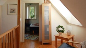 A cozy room with a wooden floor, a bed, a tall cabinet, a small table with a plant, and a window with a view of trees. - Stunning Home in Visby With 2 Bedrooms and Wifi (Visby)