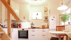 A compact kitchen with white cabinets, a stove, oven, and a dining area with a table and chair. - Stunning Home in Visby With 2 Bedrooms and Wifi (Visby)