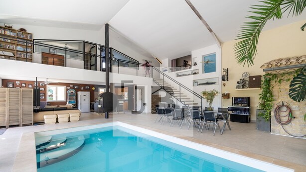 A spacious indoor swimming pool with a modern design, a staircase leading to an upper level, and a variety of seating and decorative elements. - Domaine des Vergers (Cavaillon)