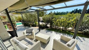 An outdoor patio with wicker furniture and a pool in the background. - Domaine des Vergers (Cavaillon)