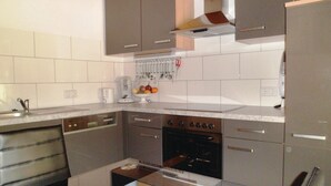 A compact kitchen with a built-in oven, a coffee maker, and a fruit bowl on the counter.