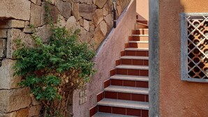A staircase leading to a building with a stone wall and a metal gate.