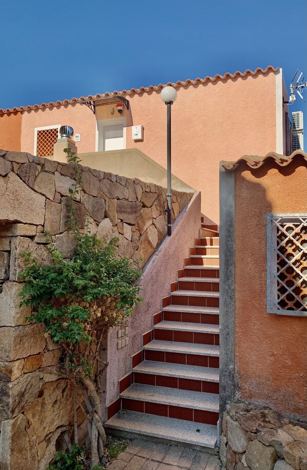 A staircase leading to a building with a stone wall and a metal gate.