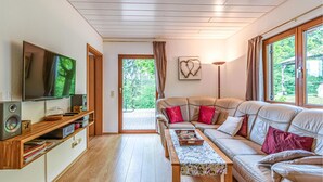 A modern living room with a sofa, television, wooden shelves, and a view of greenery outside. - Nice Home in Kirchheim With 5 Bedrooms and Wifi (Kirchheim)
