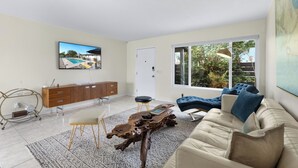 A modern living room with a sofa, coffee table, and TV. - Holiday Pool Paradise - A Ryson Property (Palm Springs)