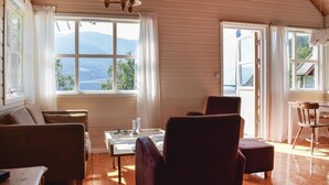 A cozy room with wooden walls, a large window with a mountain view, a table with chairs, and a sofa. - Awesome Home in Vallavik With 3 Bedrooms and Wifi (Ulvik)