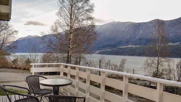 A deck with wicker chairs and a table overlooking a lake with mountains in the background. - Awesome Home in Vallavik With 3 Bedrooms and Wifi (Ulvik)