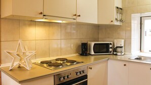 A kitchen with white cabinets, a stove, a microwave, and a coffee maker. - Vakantiewoning 10 (Simpelveld)
