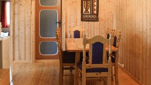 A wooden interior with a dining table and chairs, a door with decorative panels, and a wall-mounted light fixture. - Awesome Home in Hurdal With 2 Bedrooms (Hurdal)