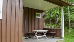 A wooden cabin with a stone patio, a table, and benches. - Awesome Home in Hurdal With 2 Bedrooms (Hurdal)