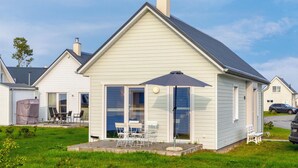 A single-story house with a gabled roof, a chimney, and a covered patio area with outdoor furniture. - Stunning Home in Ostseeresort Olpenitz With 1 Bedrooms and Wifi (Kappeln)