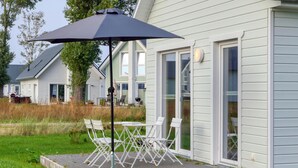 A patio with outdoor furniture and a large umbrella, adjacent to a house with sliding glass doors. - Stunning Home in Ostseeresort Olpenitz With 1 Bedrooms and Wifi (Kappeln)
