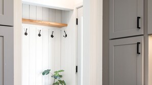 A kitchen with grey cabinets, a wooden shelf, and a potted plant. - MINNeSTAY* Shoreline Villa | Pool (Robbinsdale)