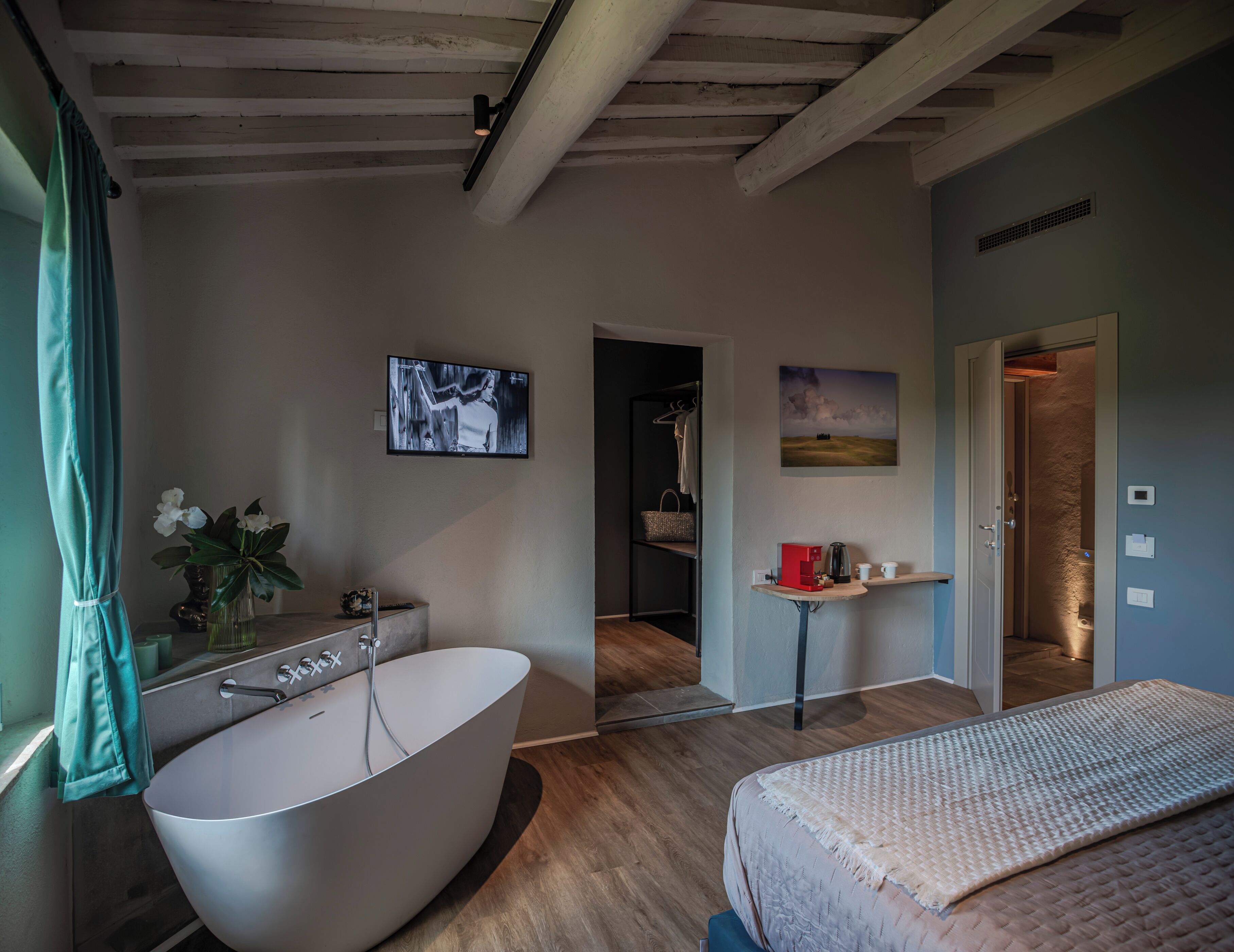 A modern bathroom with a freestanding bathtub, a vanity with a mirror, and a wall-mounted TV.