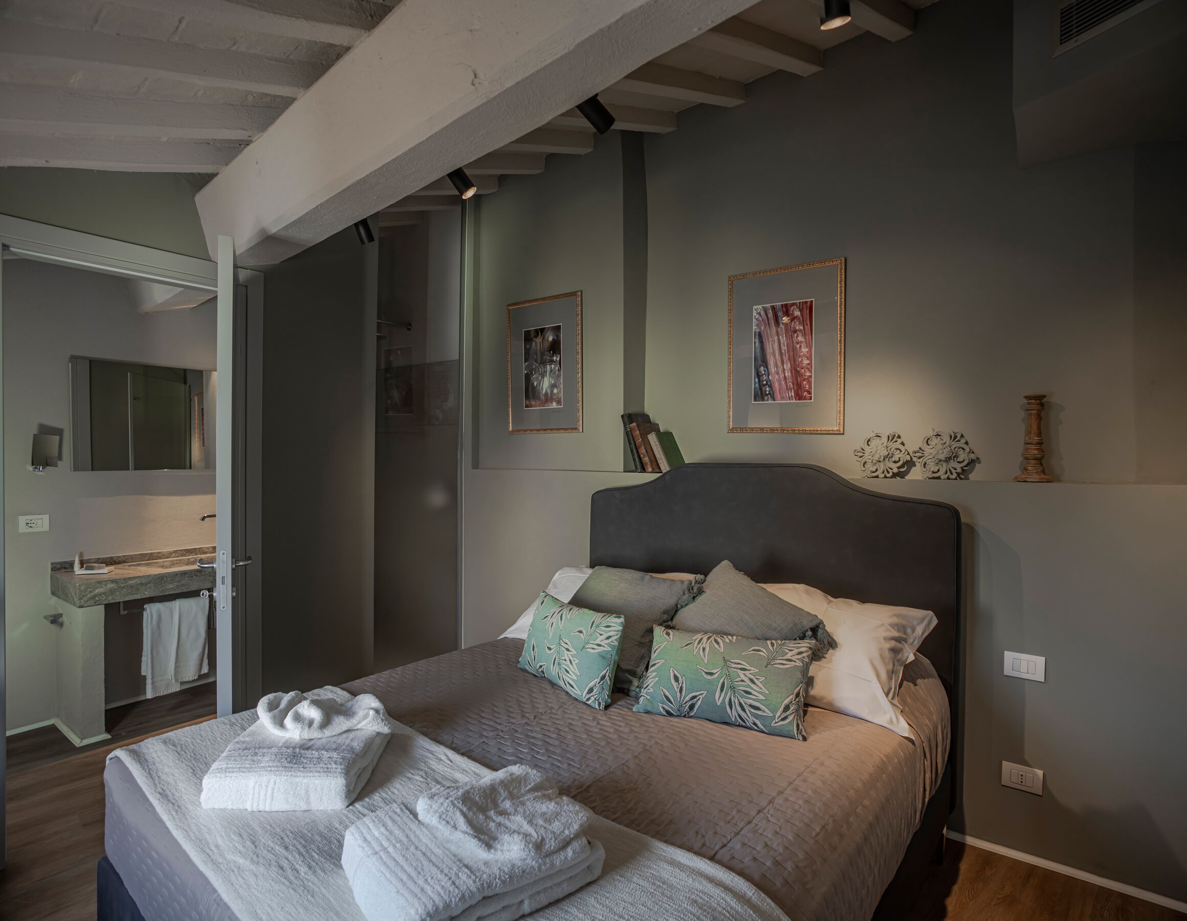 A bedroom with a bed, pillows, and a bedside table.