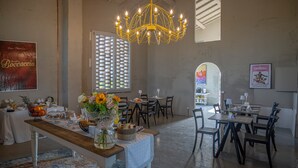 A dining area with a chandelier, tables, chairs, and a buffet table with food and drinks. - Borgo Elissa (Certaldo)