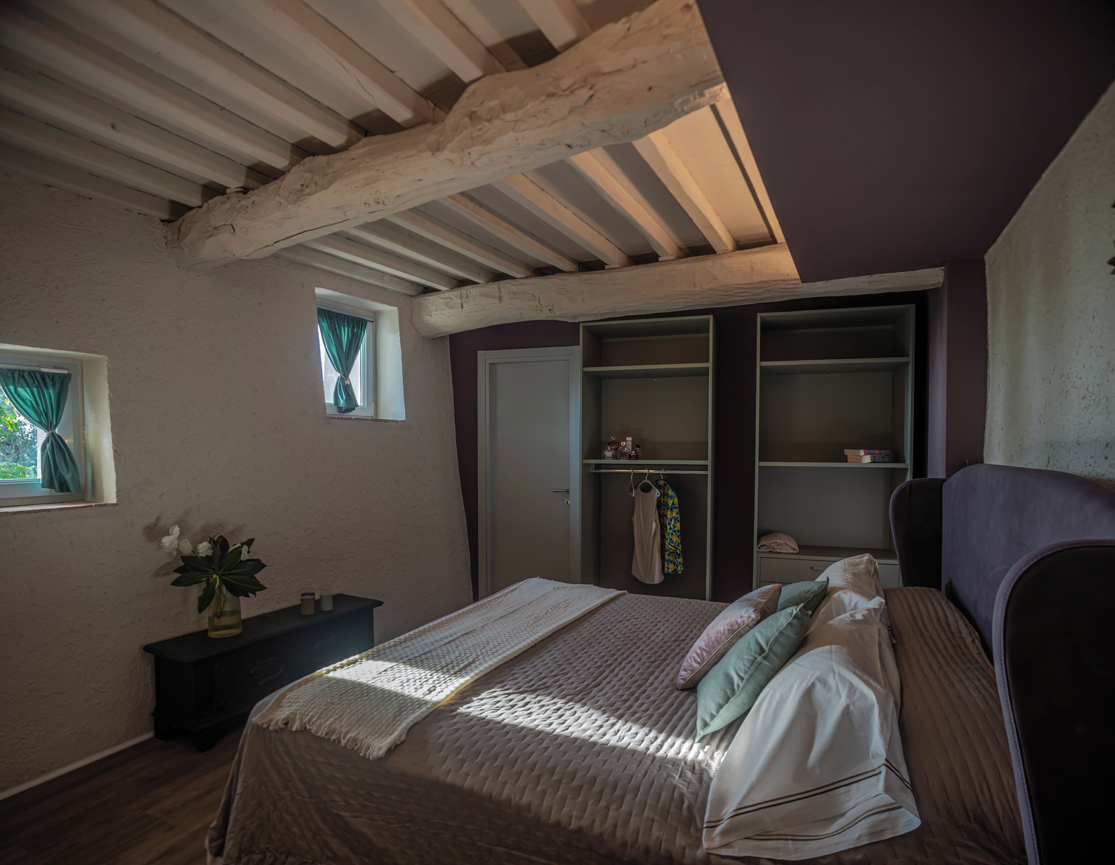 A bedroom with a bed, a window with curtains, a dresser, and a built-in wardrobe.