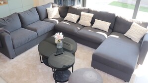 A modern living room with a grey sectional sofa, a round coffee table, and a small ottoman. - Luxusvilla - 150 Meter vom Meer Neu in 2023 (Banjole)