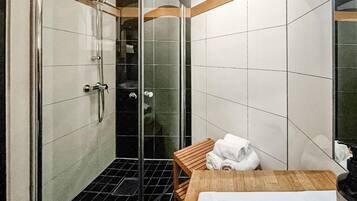 A modern bathroom with a glass-enclosed shower, a wooden vanity, and a white bathtub.