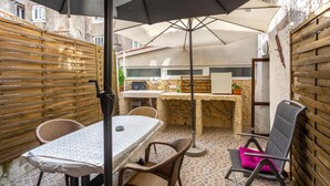 Une terrasse extérieure avec une table, des chaises et une cheminée en pierre.