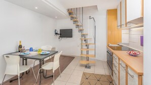Une cuisine compacte dotée d’un plan de travail en bois, d’un four encastré et d’un petit coin repas avec une table et des chaises.