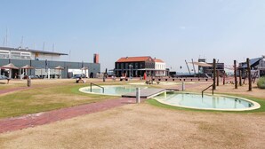 Une zone riveraine dotée d’une piscine, d’un magasin de planches de stand-up paddle et d’un bâtiment au toit rouge.