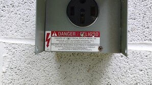 Un cuadro eléctrico con una etiqueta de advertencia y un enchufe.