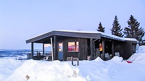 A wooden cabin with a covered porch and a bench, surrounded by snow. - Beautiful Home in Gol With 2 Bedrooms (Gol)