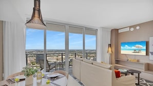 Ein modernes Hotelzimmer mit Balkon, Essbereich, Sofa und Fernseher.