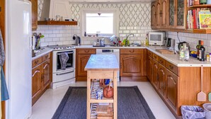 A kitchen with wooden cabinets, a built-in oven, a small table, and a window. - Beautiful Home in Varberg With Wifi and 4 Bedrooms (Varberg)