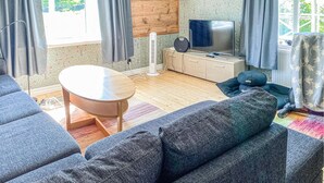 A modern living room with a sofa, a small round table, a television, and a speaker. - Beautiful Home in Varberg With Wifi and 4 Bedrooms (Varberg)