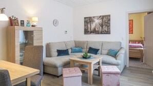 Una sala de estar con un sofá, dos otomanas, una mesa de madera y una lámpara.