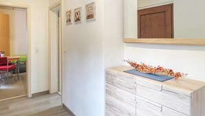 Un pasillo con un aparador de madera, un espejo y cuadros en la pared.