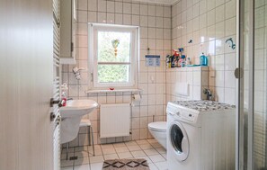 Een kleine badkamer met een wastafel, toilet en wasmachine.