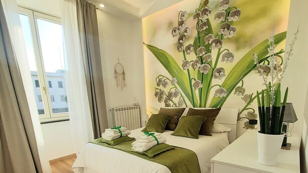 Um quarto moderno com uma cama grande, uma mesa de cabeceira, um radiador e um sonho apanhador fixado na parede.