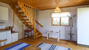 Interior de madera con una escalera, una ventana con vistas, un radiador y una pequeña mesa con velas.