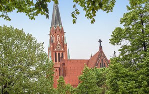 Une église historique, dotée d’un flèche imposante et d’une tour horloge, entourée d’arbres verdoyants.