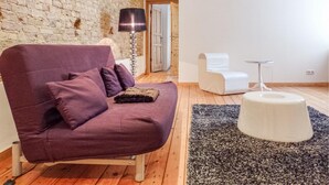 A modern living room with a purple sofa, a white chair, a small round table, and a lamp. - Beautiful Apartment in Berlin With 1 Bedrooms and Wifi (Berlin)