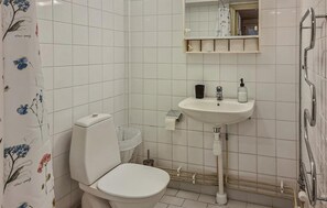A bathroom with a toilet, sink, and mirror.
