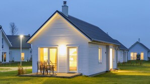 Een klein, laag huis met een schuin dak en een veranda.