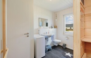 Een kleine badkamer met een wit wastafel, toilet en een klein opstapkrukje.