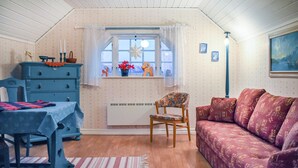 A cozy room with a blue table, a patterned sofa, a wooden chair, and a window with decorative items. - Beautiful Home in Asarum With (Asarum)