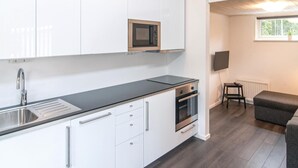 A modern kitchen with white cabinets, a black countertop, a microwave, an oven, and a built-in dishwasher. There is a window with a view of greenery outside. - Amazing Home in Gotlands Tofta With 2 Bedrooms (Gotlands Tofta)