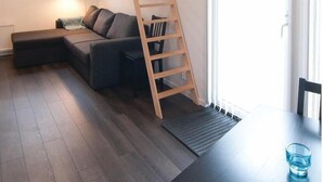 A modern living room with a wooden loft bed, a dark sofa, and a dining table. - Amazing Home in Gotlands Tofta With 2 Bedrooms (Gotlands Tofta)