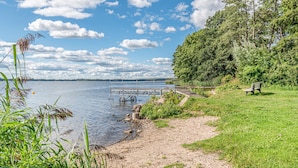 A lakeside park with a wooden dock, a grassy area, and a bench. - Hotel Wittensee (Gross Wittensee)
