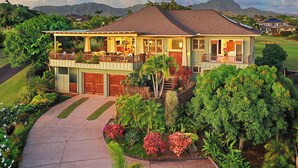 Una casa de dos pisos con un porche cubierto, un garaje y un jardín bien cuidado con diversas plantas y flores.