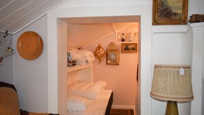 Ett sovrum med en våningssäng, en trästol, en lampa och en väggklocka.