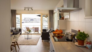 A modern kitchen with a dining area, a view of a marina, and a balcony with outdoor seating. - Aqualiving (Aalsmeer)
